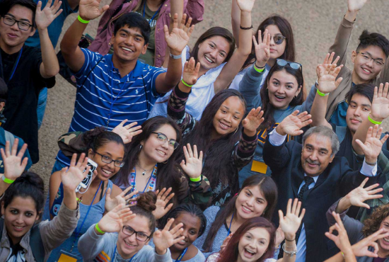 Chancellor' Khosla surrounded by UC San Diego students, hands raised in celebration.