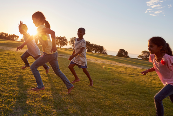 children running in a field with sunshine